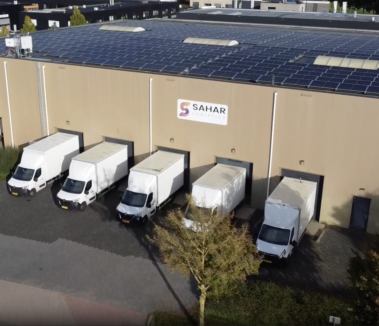 hier zie je 8 vrachtauto's met een heel groot pand met het logo van Sahar logistics